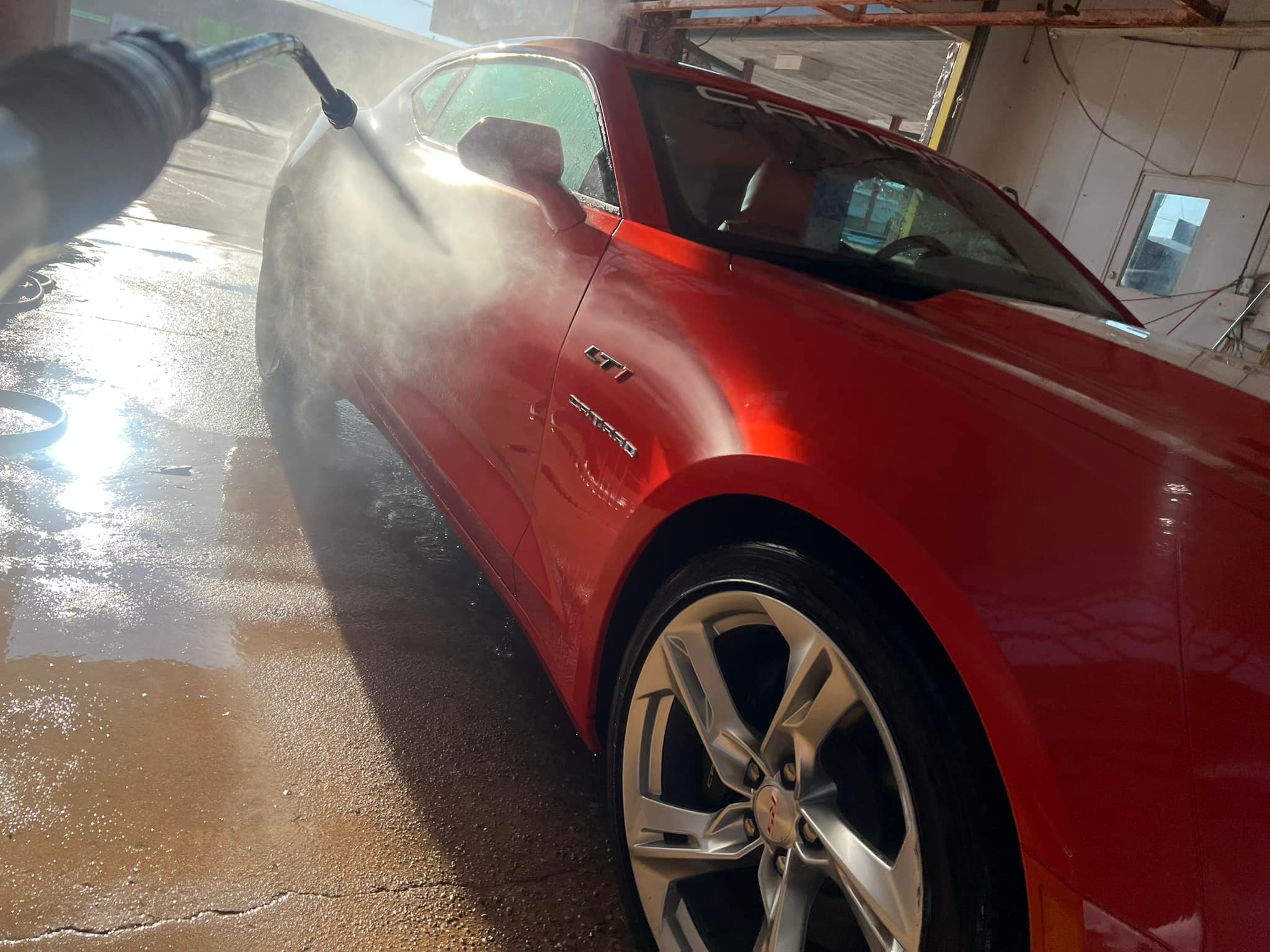 Red Chevrolet Camaro being rinsed down after a hand wash at Texas Car Detail in Dublin, TX